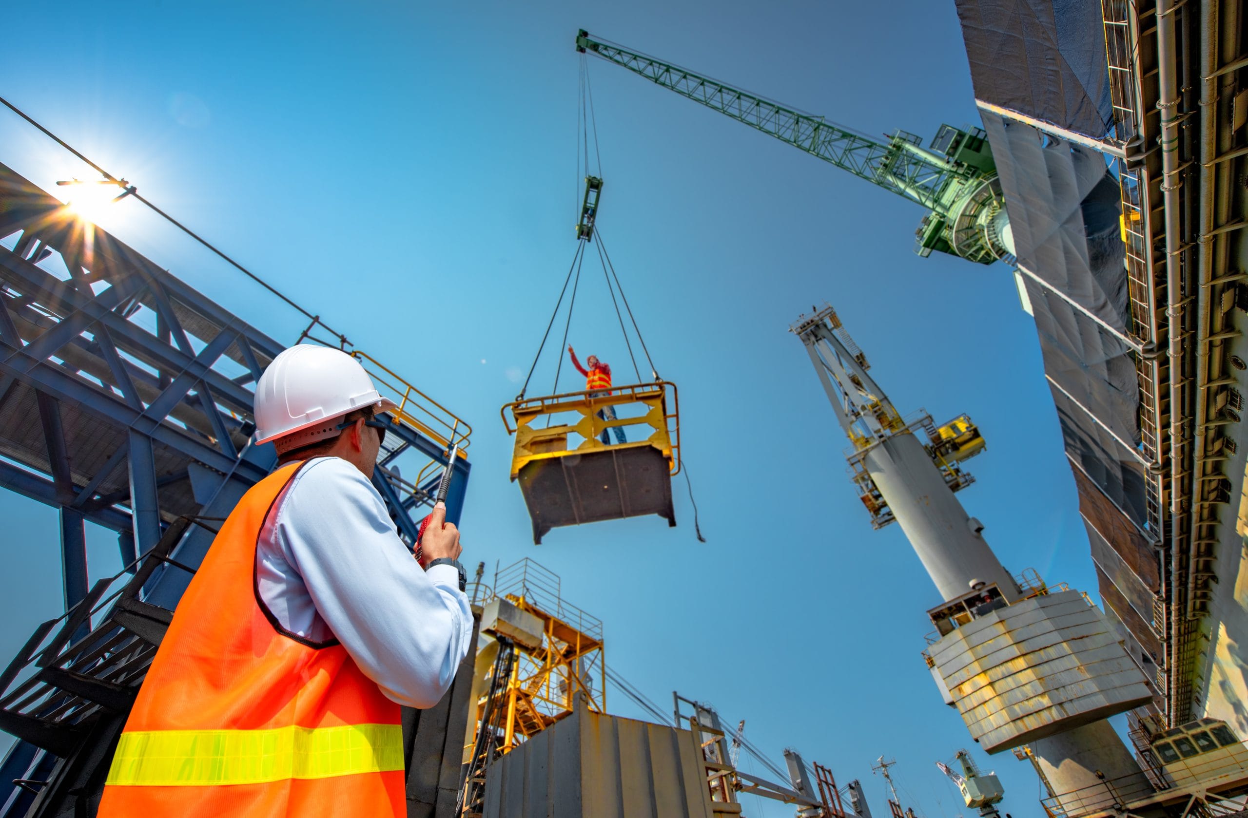Construction worker with walkie talkie slinger/signalling crane to safely carry out the work on the construction site