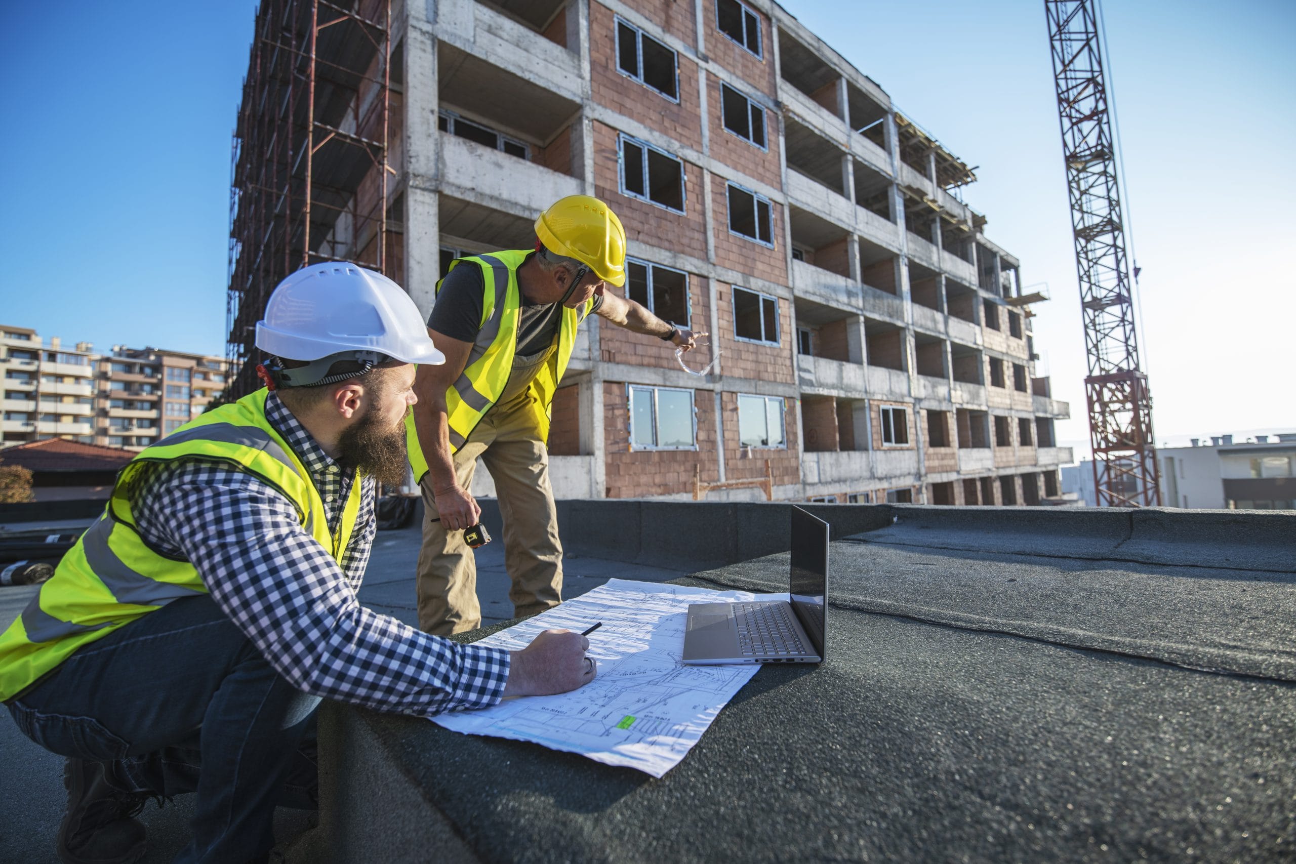 SSSTS Construction site supervisors reviewing the site map, planning and monitoring the work in front of a half-built building.