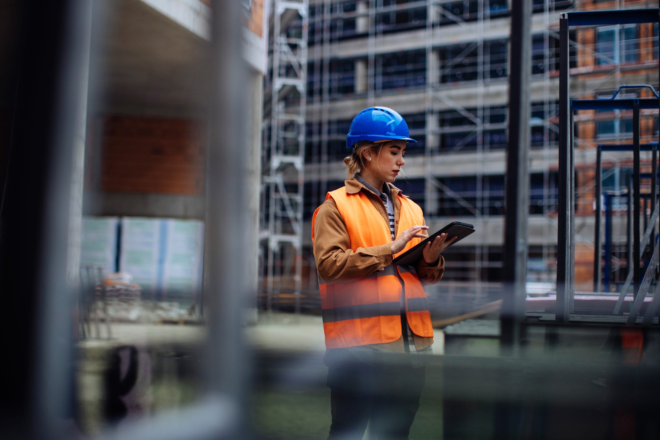 Occupational Health & Safety specialist using a tablet to carry out a safety inspection of the construction site.