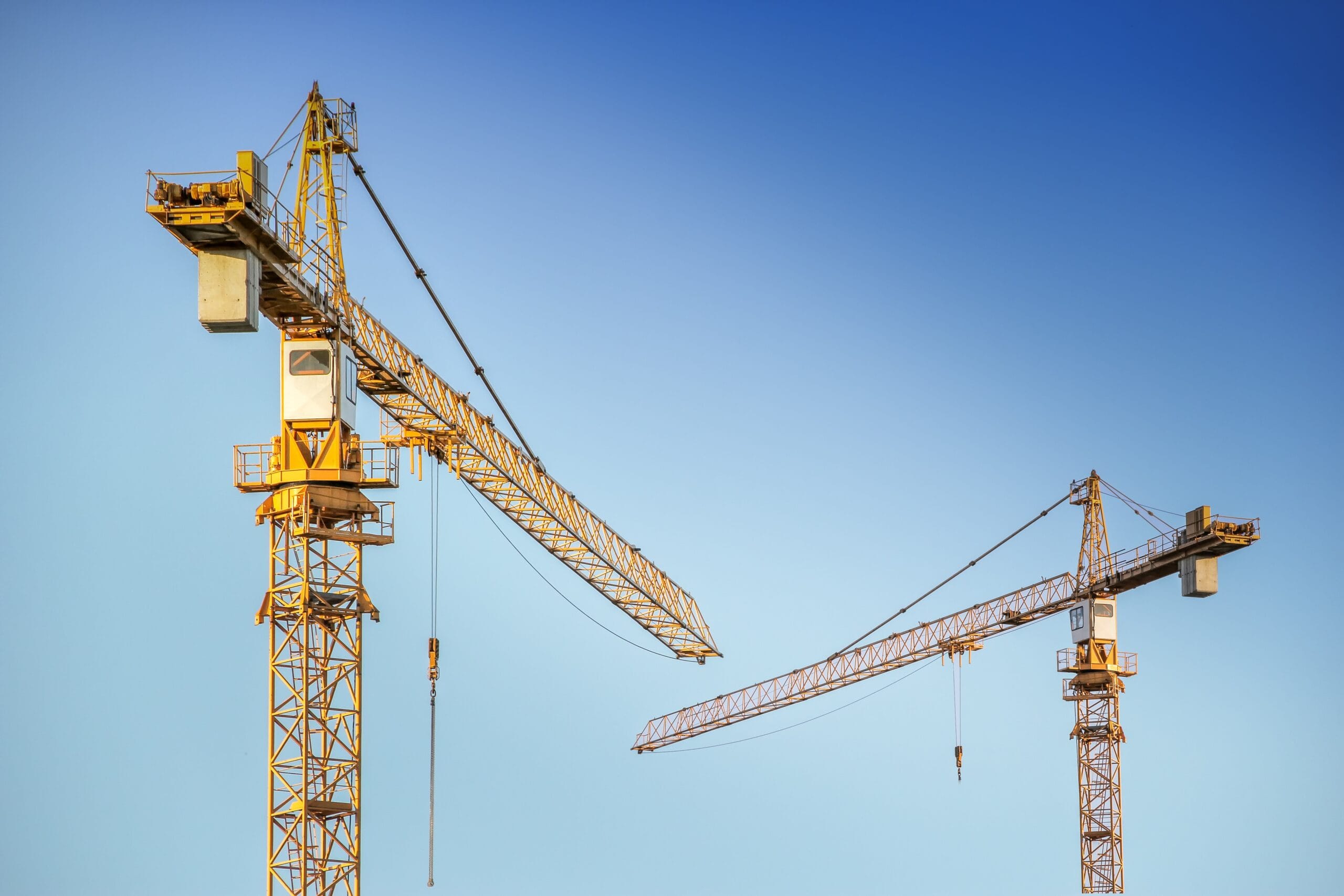Construction cranes against a bright blue sky